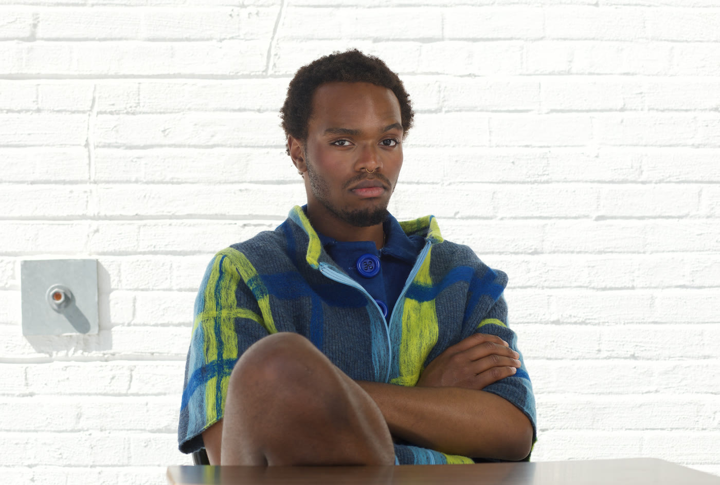 Editorial photograph — model at a table in a plaid polo
