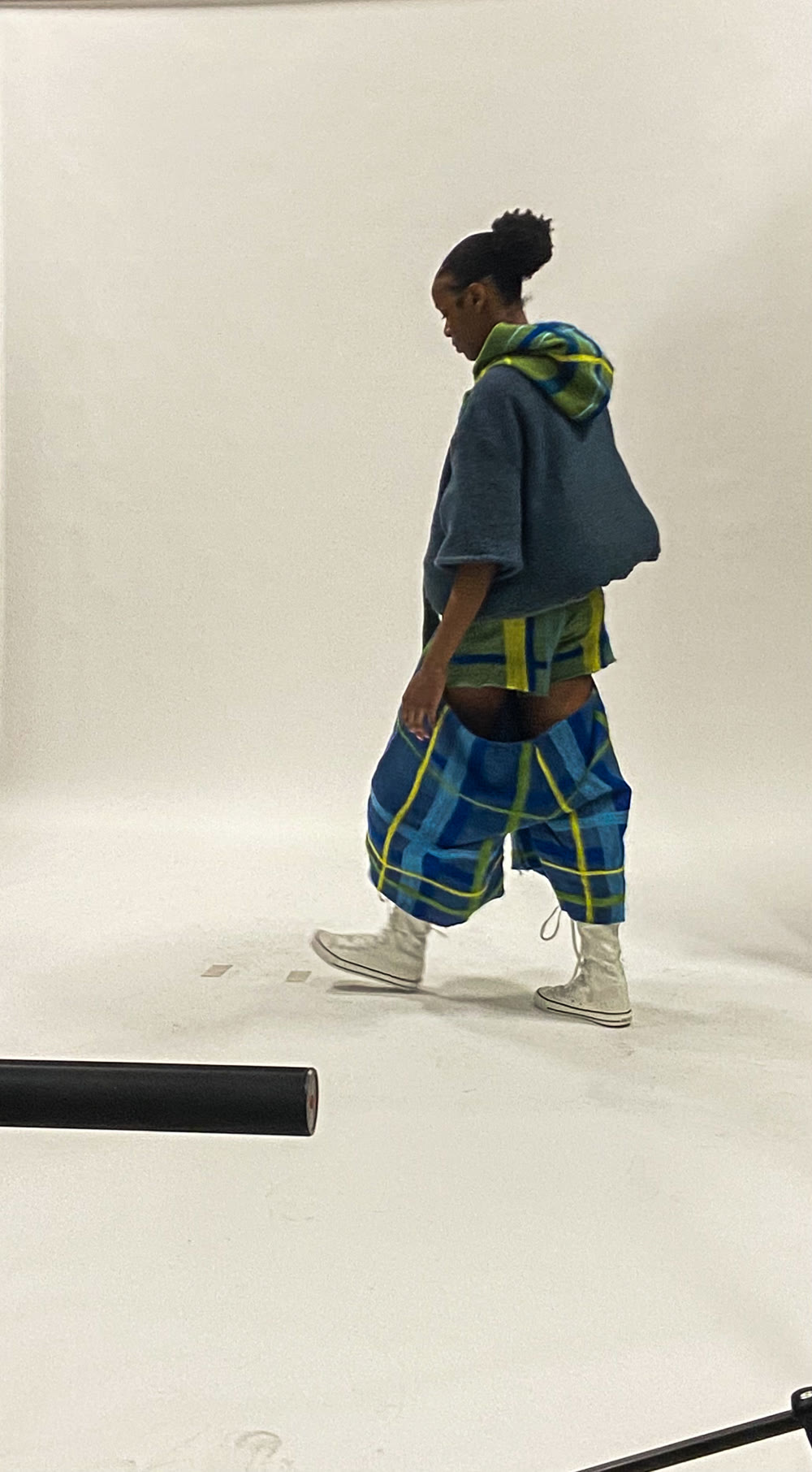 Finished look — felted hooded capelet over drop-waist plaid trousers, in motion
